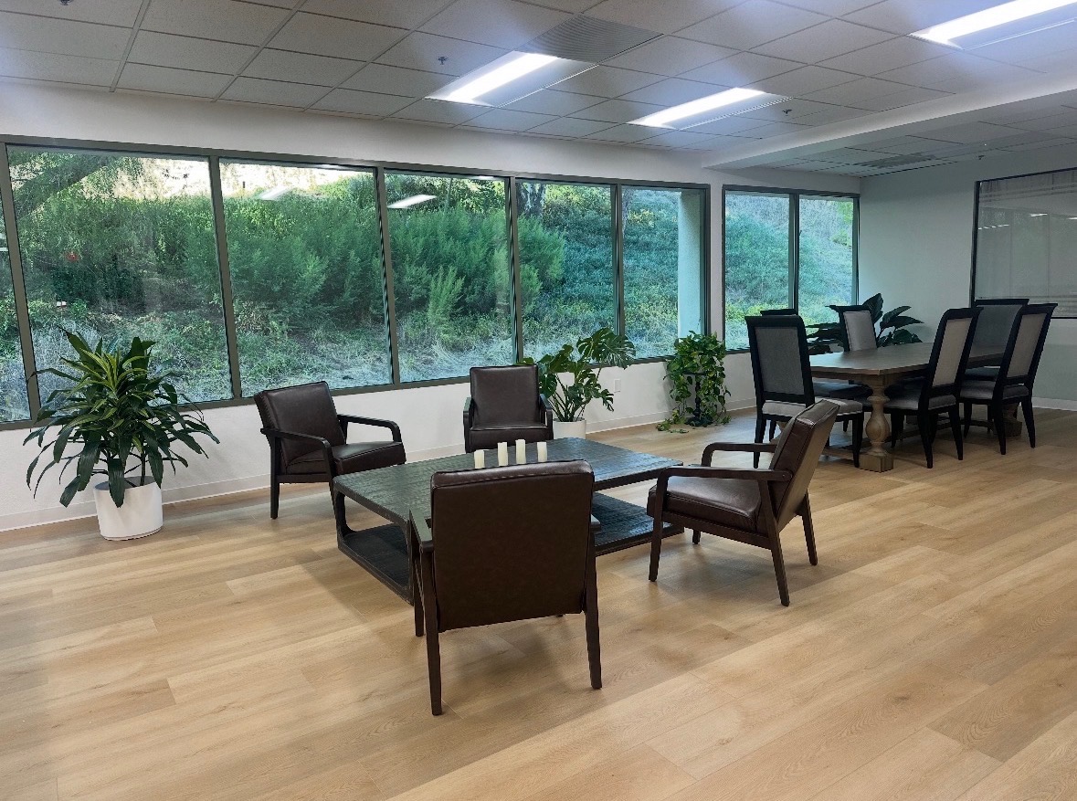 Moonglade Recovery meeting area with chairs around a coffee table, a conference table, plants, and large windows